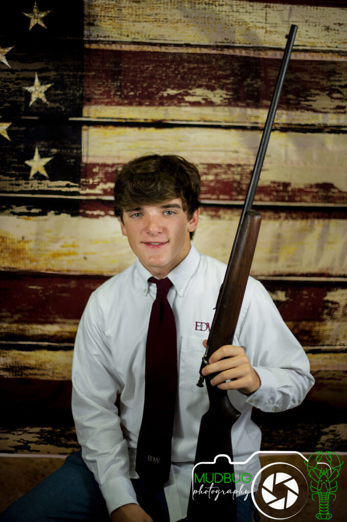 Zack with his great-grandfather's rifle in front of a distressed American flag background